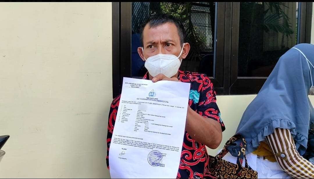 Ayah korban menunjukkan bukti laporan polisi (Foto: Rusdi/Ngopibareng.id)