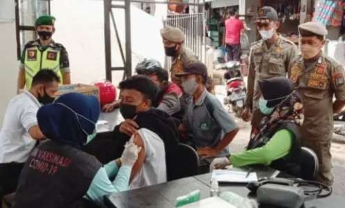 Tim gabungan melakukan vaksinasi Covid-19 kepada pengunjung Pasar Induk Bondowoso yang terjaring Operasi Yustisi Penegakan Prokes. (Foto: Dok Satpol PP)