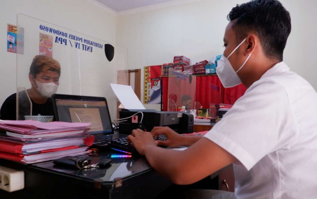 Pelaku penganiayaan berinisial RD sedang diperiksa penyidik Satreskrim Polres Bondowoso. (Foto: Guido Saphan/Ngopibareng.id)