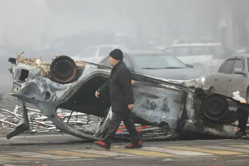 Seorang warga berjalan melewati sebuah mobil yang terbakar, selama aksi protes yang dipicu kenaikan harga bahan bakar, di Almaty, Kazakhstan. (Foto: Ant)
