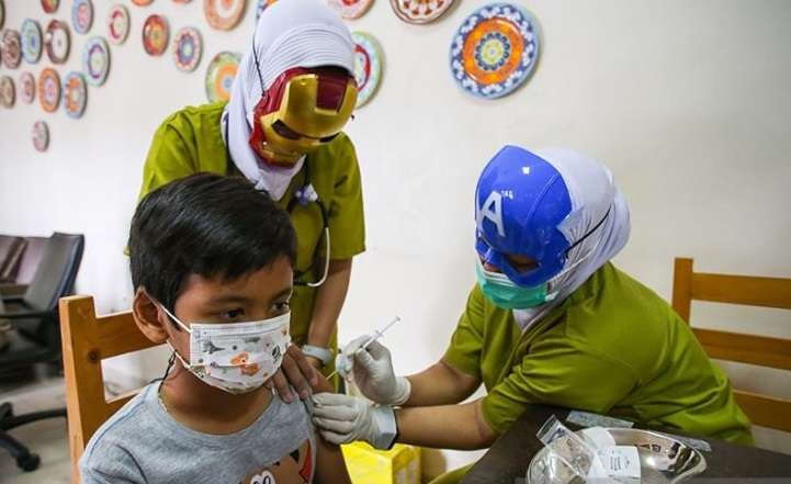Dua orang tenaga kesehatan menggunakan topeng pahlawan super saat menyuntikkan vaksin COVID-19 kepada anak usia 6-11 tahun di RSIA Tambak, Jakarta, Rabu 5 Januari 2022. Penggunaan topeng pahlawan super tersebut bertujuan menarik minat anak-anak untuk mengikuti program vaksinasi COVID-19. (Foto: Antara/Rivan Awal Lingga)