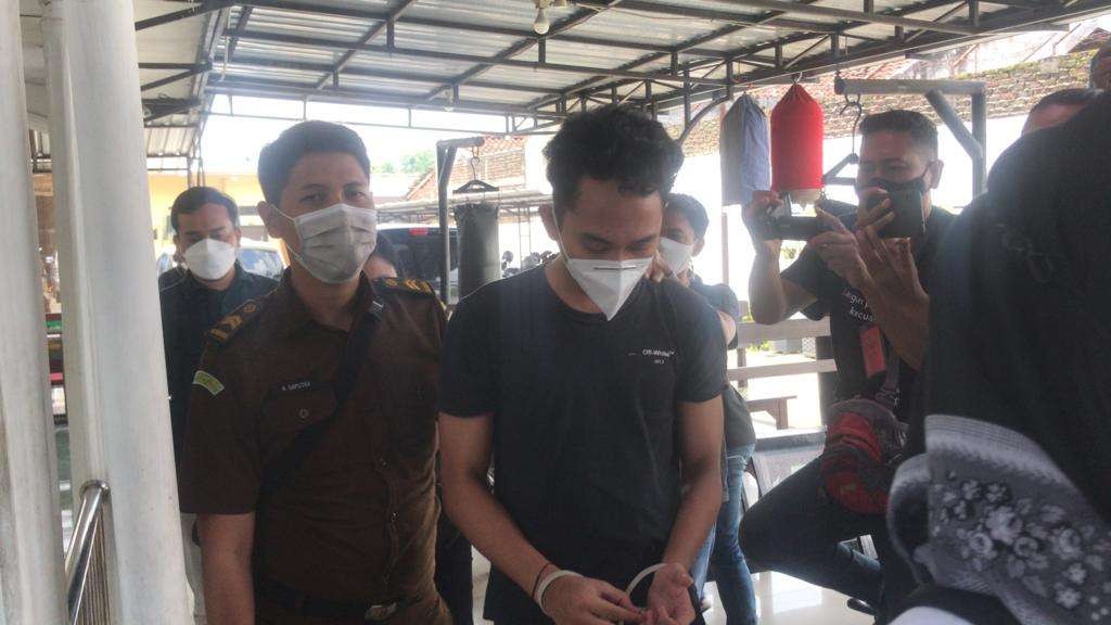 Randy memakai kaos hitam didampingi petugas Kejaksaan Negeri Kabupaten Mojokerto digelandang menuju ruang pemeriksaan.(Foto: Deni Lukmantara/Ngopibareng)