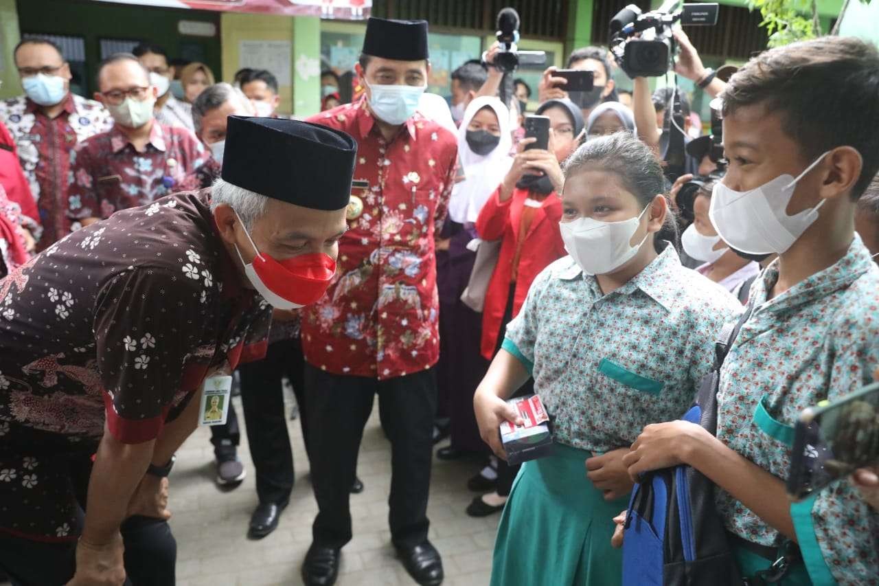 Gubernur Jawa Tengah, Ganjar Pranowo (kiri) bagi handphone untuk Nabila karena bisa jawab pertanyaan soal vaksin, Rabu 2 Februari 2022. (Foto: Istimewa)