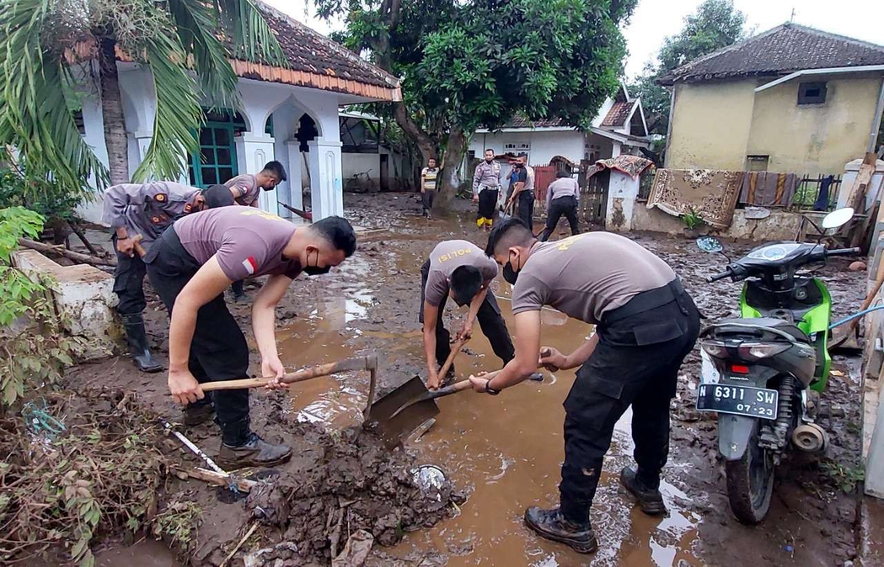 Jajaran Polresta Probolinggo membersihkan endapan lumpur pasca banjir di Desa Tambakrejo, Kecamatan Tongas. (Foto: Ikhsan Mahmudi/Ngopibareng.id)