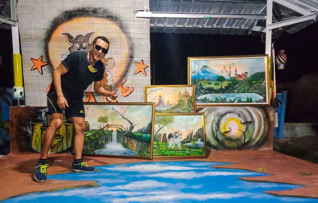 Yulius Heru Sutejo pose bersama karya lukisnya. (Foto: Istimewa)