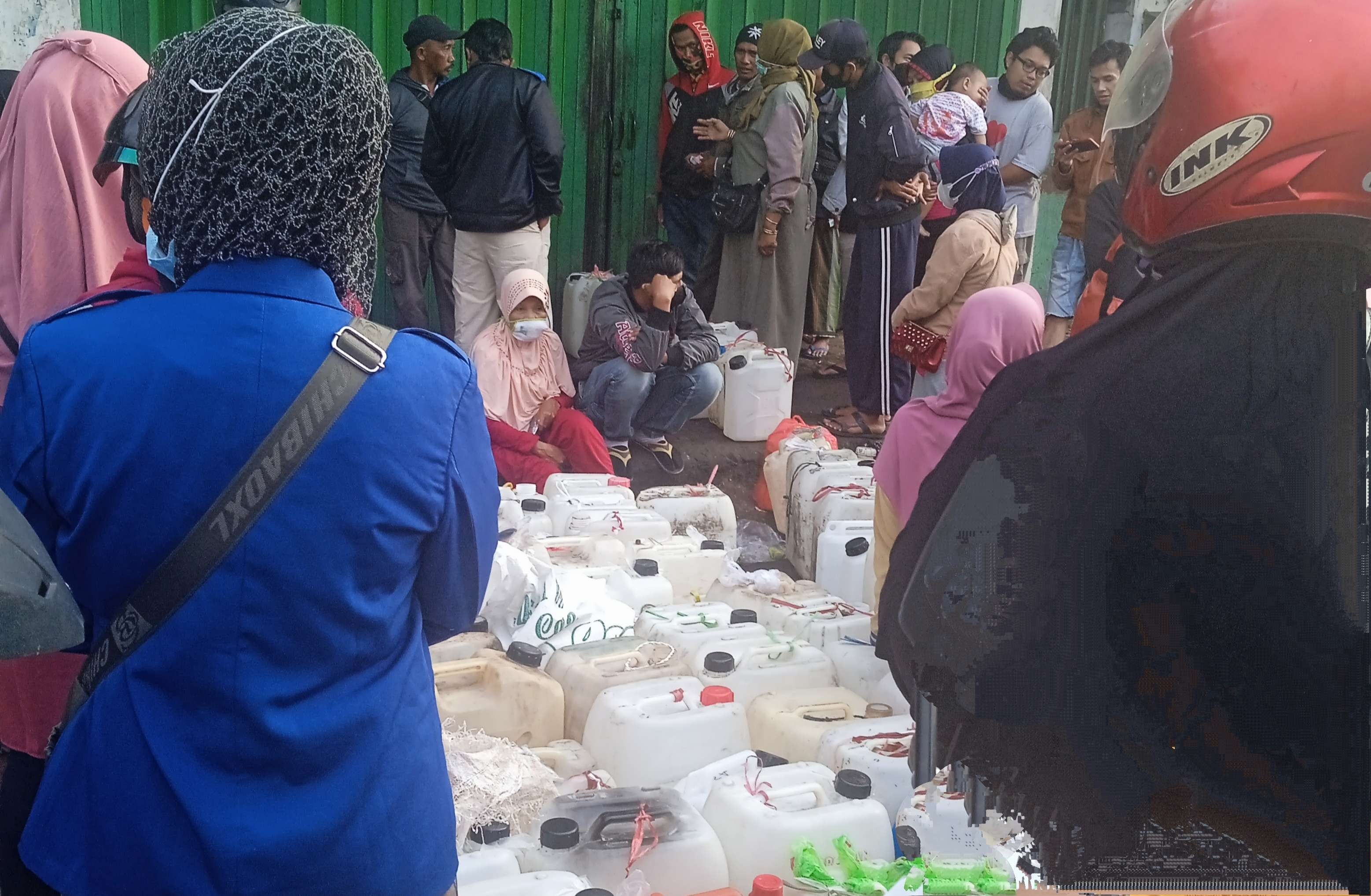 Warga Bondowoso membawa jerigen antre membeli minyak goreng di salah satu pangkalan minyak goreng. (foto:guidi/ngopibareng.id)