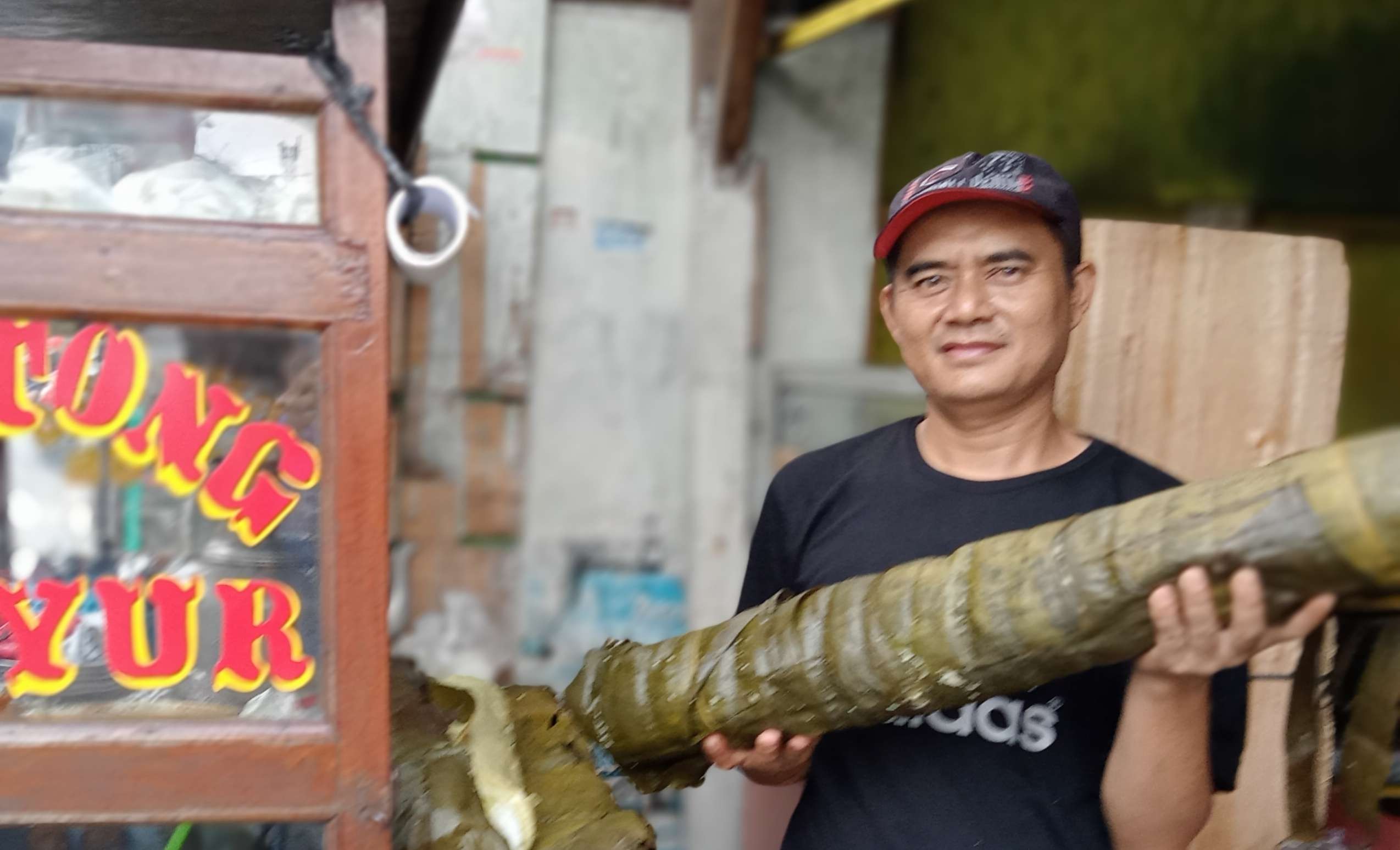 Pedagang lontong sayur Garut Asep memamerkan lontongnya yang segede tiang listrik. (Foto: Asmanu Sudharso/Ngopibareng.id)