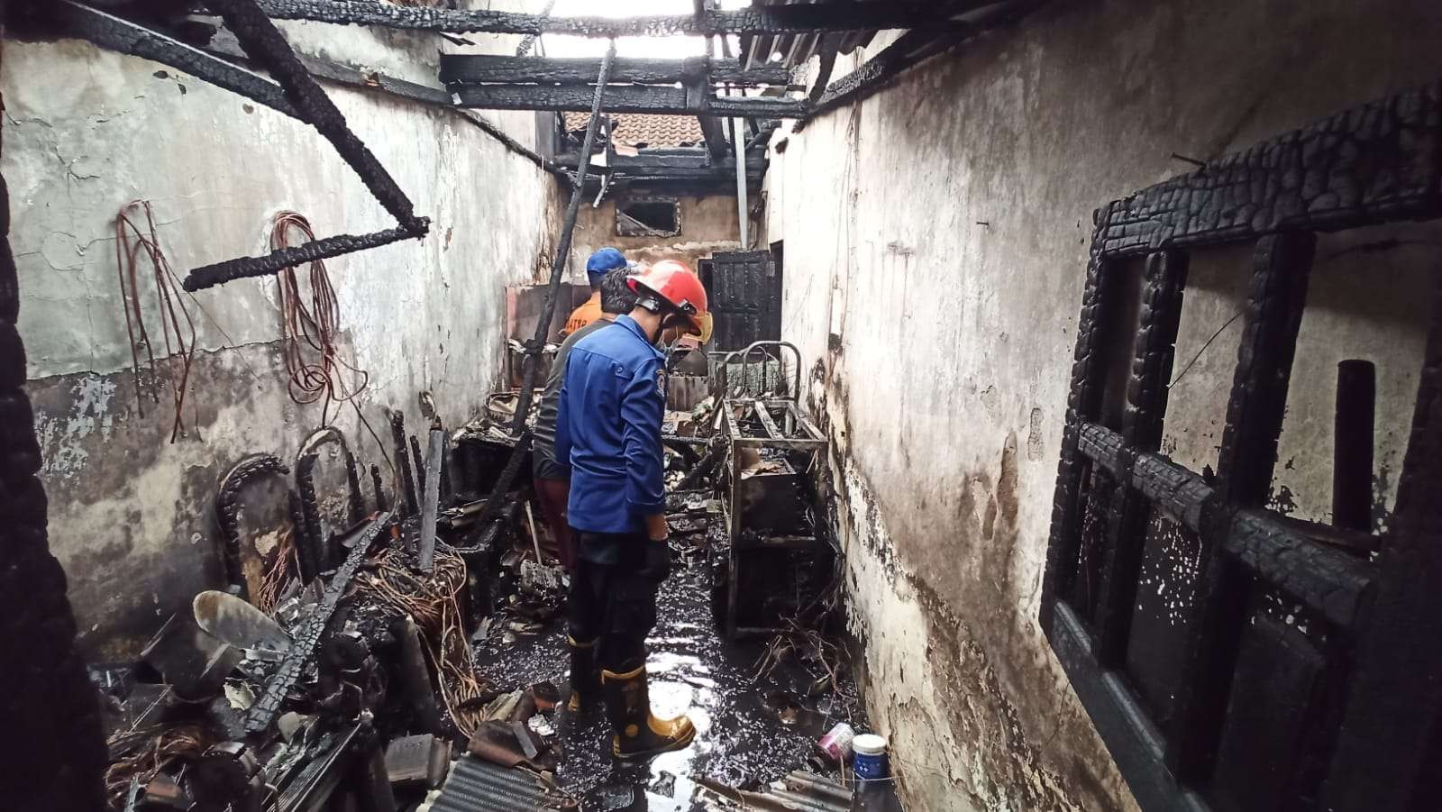 Petugas pemadam kebakaran mencermati bagian dapur rumah korban yang diduga tempat munculnya api (Foto: Muh Hujaini/Ngopibareng.id)