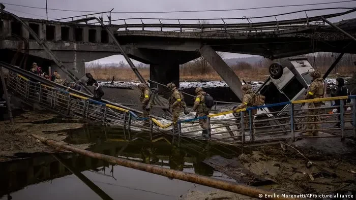 Tentara Ukraina melintasi jembatan yang hancur, di pinggiran Kyiv, Ukraina, Rabu, 2 Maret 2022. (Foto: dw.com)