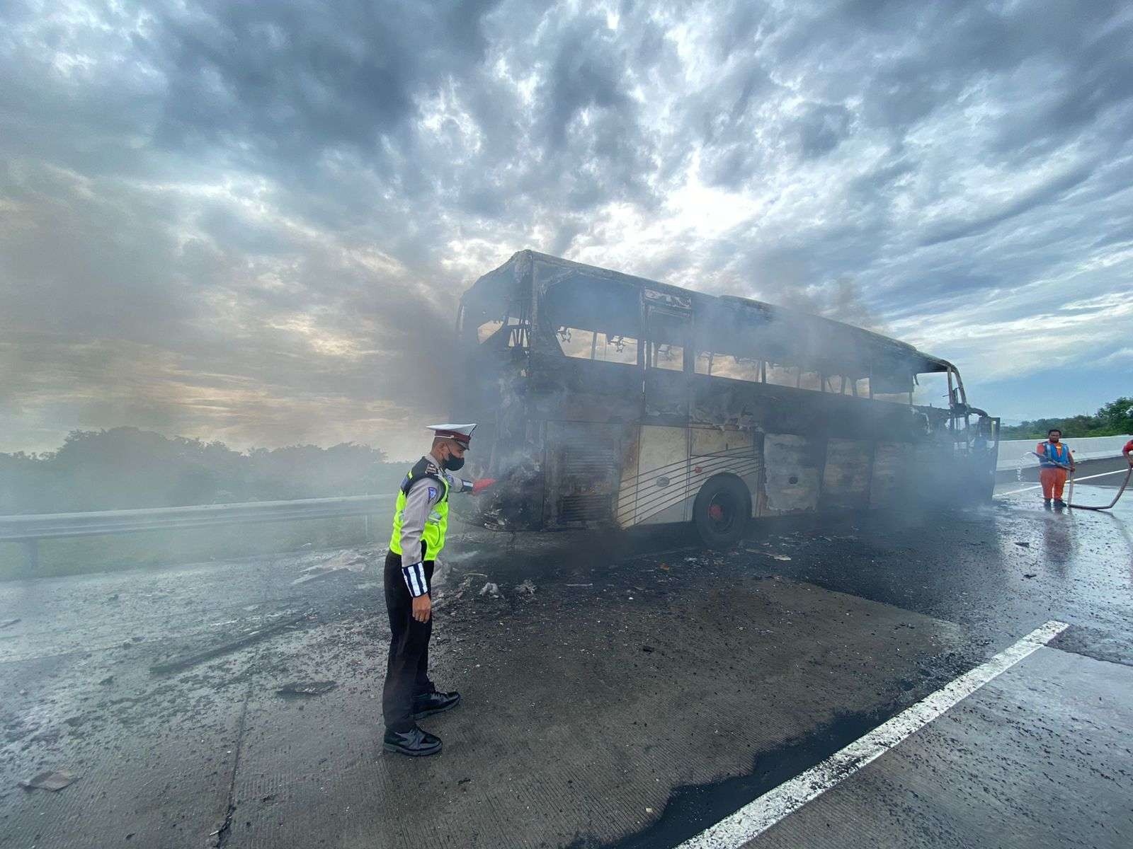 Petugas kepolisian membantu evakuasi bus yang terbakar di Tol Pandaan-Malang, Minggu 6 Maret 2022. (Foto: istimewa)