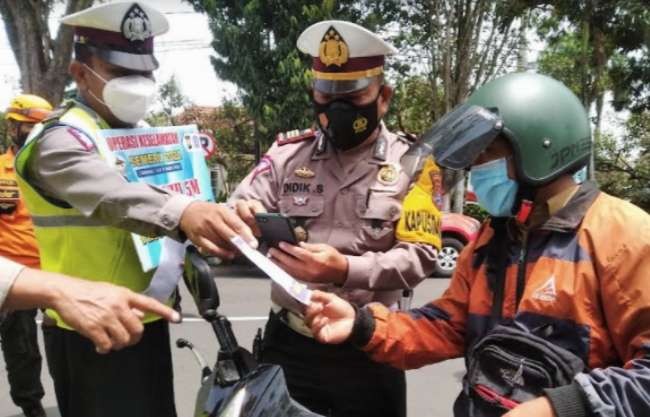 Anggota Satlantas Polres Bondowoso memeriksa kelengkapan surat pengendara dalam aksi simpati Operasi Keselamatan Semeru 2022. (Foto: Guido/Ngopibareng.id)