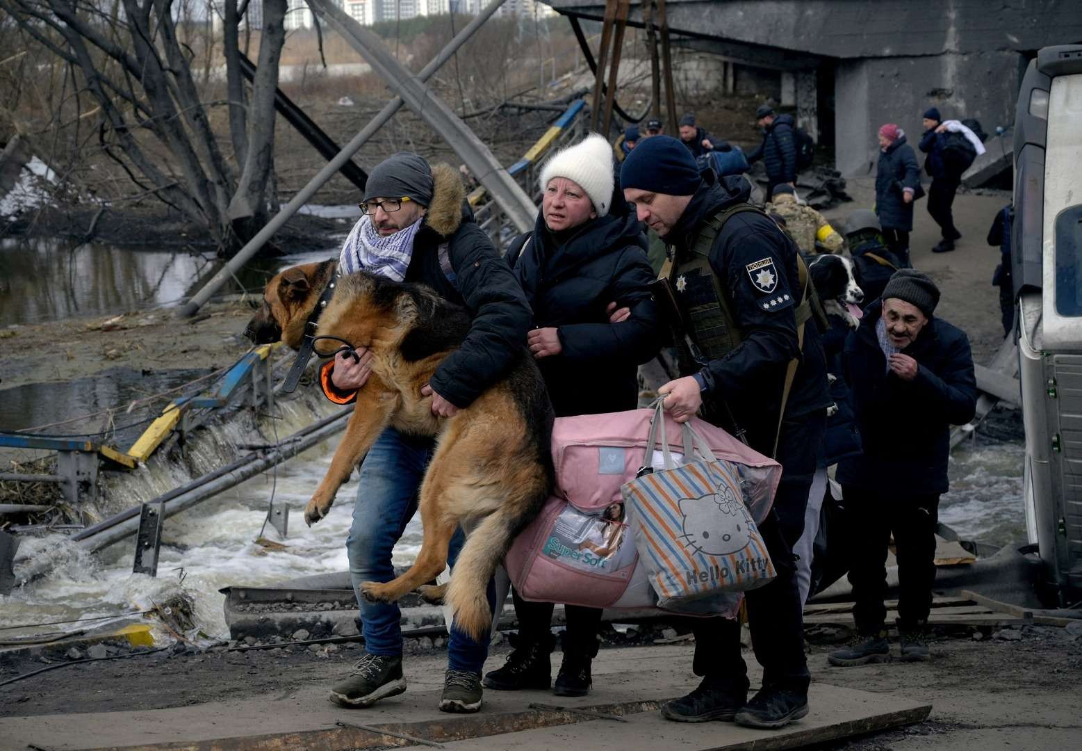 Seorang pria menggendong anjingnya saat warga menyelamatkan diri dari invasi Rusia di Ukraina, di Romanivka, Ukraina. (Foto: Reuters)