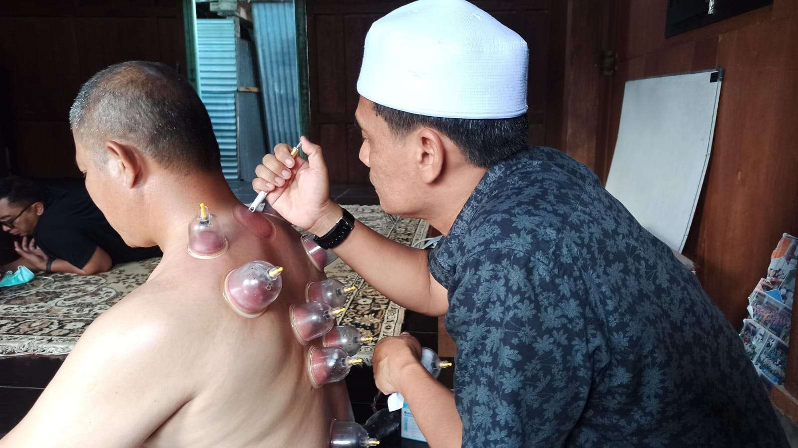 Ahmad Effendi sedang memberikan terapi bekam kepada salah seorang warga. (Foto: Muh Hujaini/Ngopibareng.id)