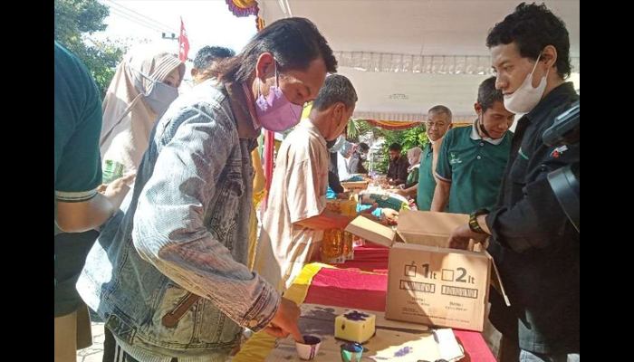 Masyarakat celupkan jarinya ke tinta sebelum berbelanja di pasar pangan murah di Tuban (Khoirul Huda/Ngopibareng.id)