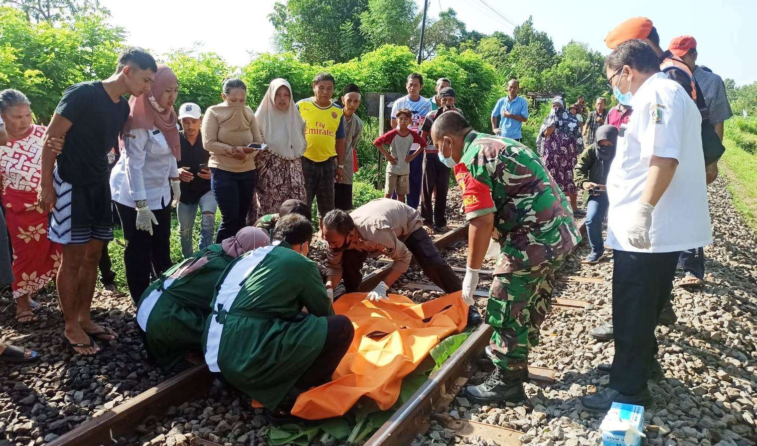 Petugas mengevakuasi jenazah perempuan yang tewas akibat tertabrak Kereta api (Foto: Muh Hujaini/Ngopibareng.id)