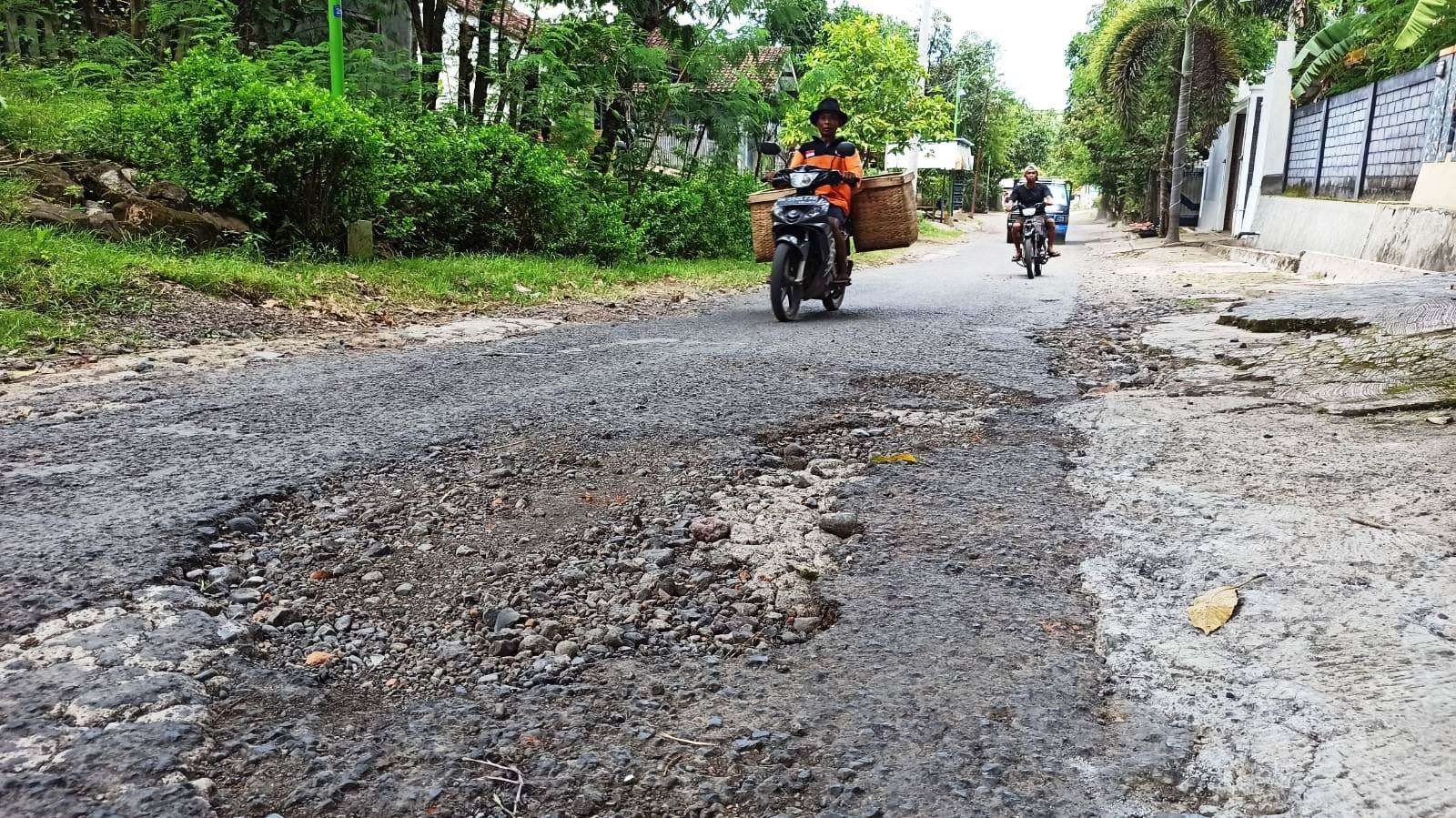 Pengguna motor melintas di Jalan Akasia, Giri, Banyuwangi, Jawa Timur. Akses jalan ini mengalami kerusakan cukup parah. (Foto: Muh Hujaini/Ngopibareng.id)
