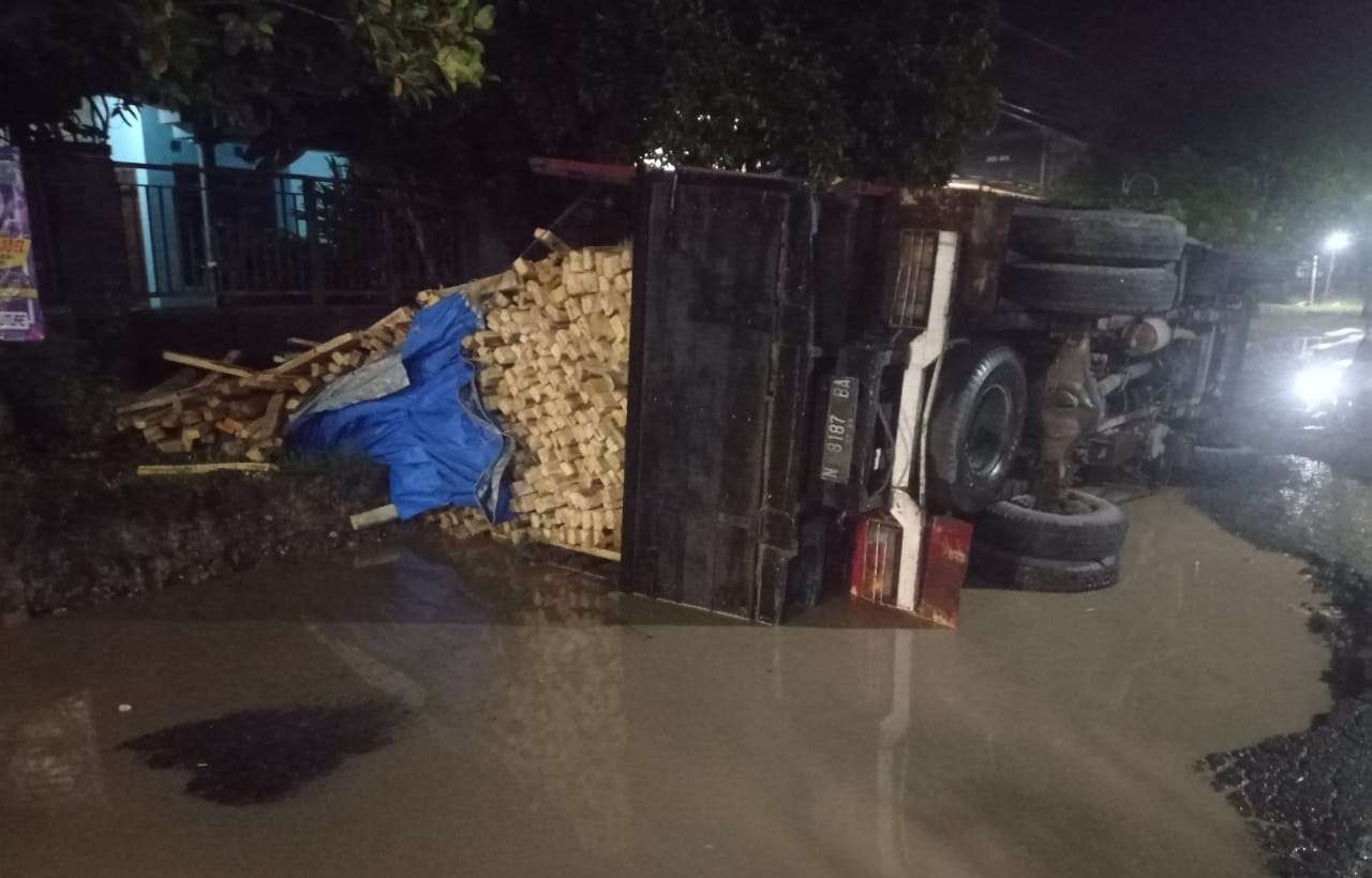 Truk bermuatan kayu terguling karena terperosok di kubangan jalan raya Desa Menongo, Kecamatan Sukodadi, lepas Subuh, Kamis 4 April 2022. (Foto: Istimewa)
