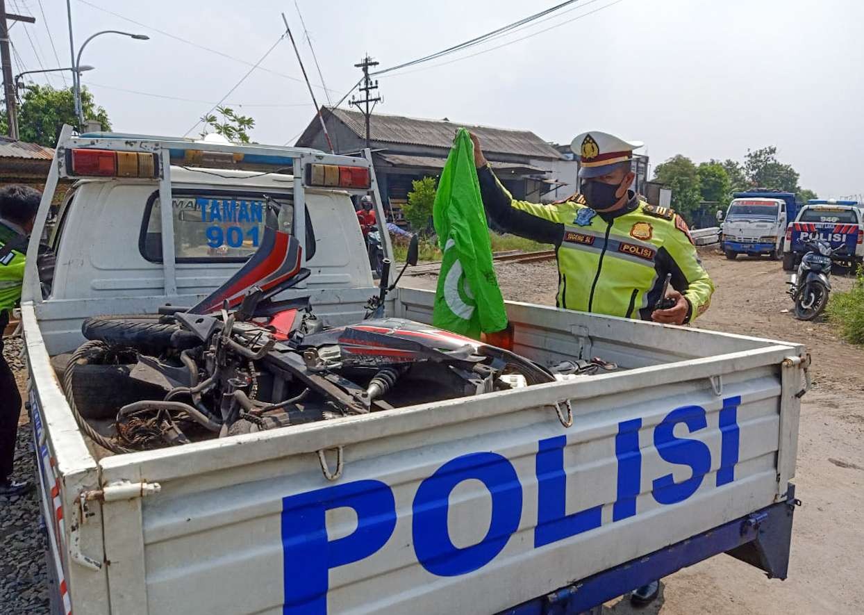 Polisi mengevakuasi motor korban kecelakaan yang melibatkan seorang pengemudi ojek online tertabrak KA Jenggala rute Surabaya-Mojokerto di Pos Klutuk Sidoarjo, Sabtu 9 April 2022. (Foto: Istimewa)