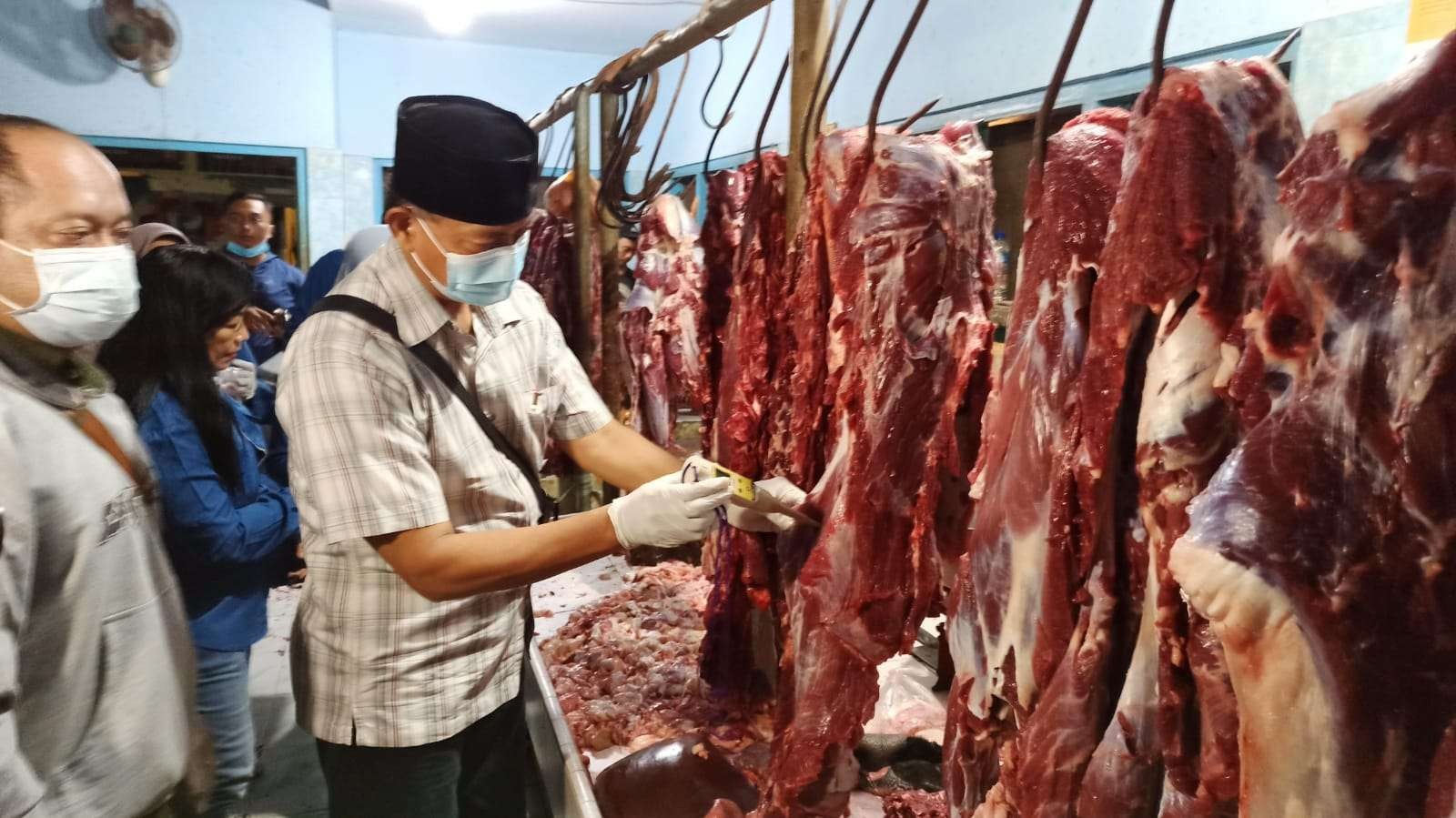 Pelaksana Tugas Kepala Dinas Pertanian dan Pangan Banyuwangi, M. Khoiri mengecek kadar PH daging sapi yang dijual di Pasar Blambangan, Selasa 26 April 2022. (Foto: Muh. Hujaini/Ngopibareng.id)