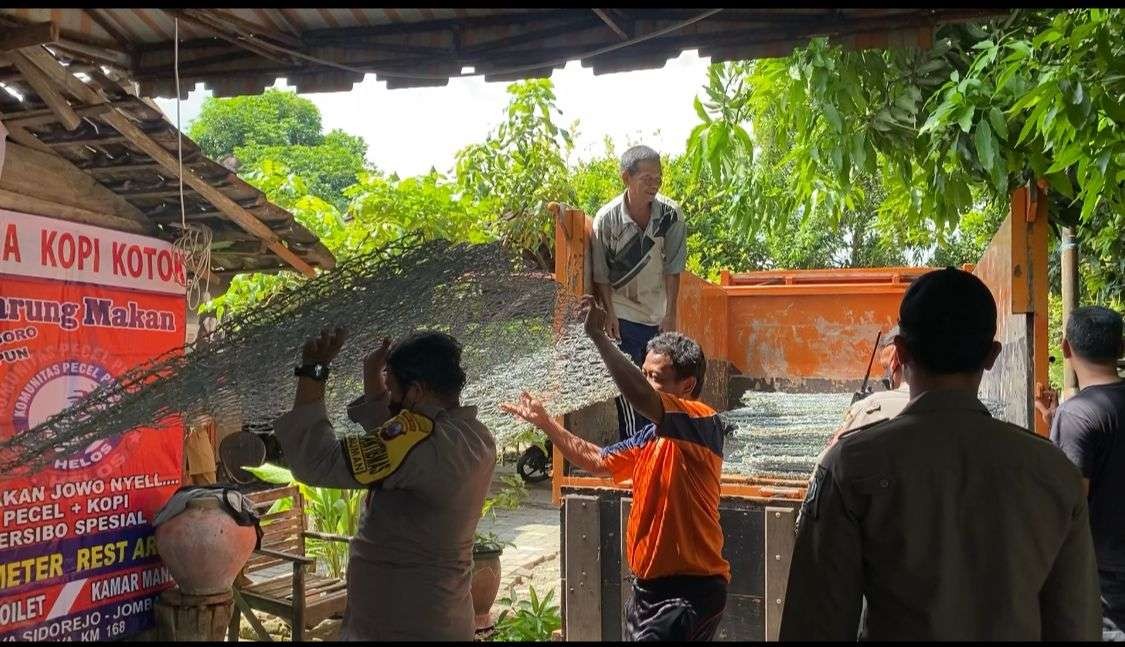Warga dan aparat gabungan gotong royong memperbaiki rumah yang tanahnya ambles akibat longsor di tepi Sungai Bengawan Solo.(Foto: DokumentasiPolres Bojonegoro/Ngopibareng.id)