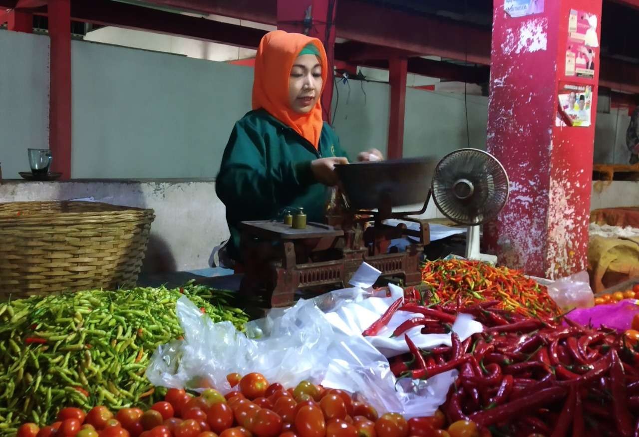 Seorang pedagang di Pasar Baru, Kota Probolinggo menawarkan cabai rawit segar dan cabai rawit kering. (Foto: Ikhsan Mahmudi/Ngopibareng.id)