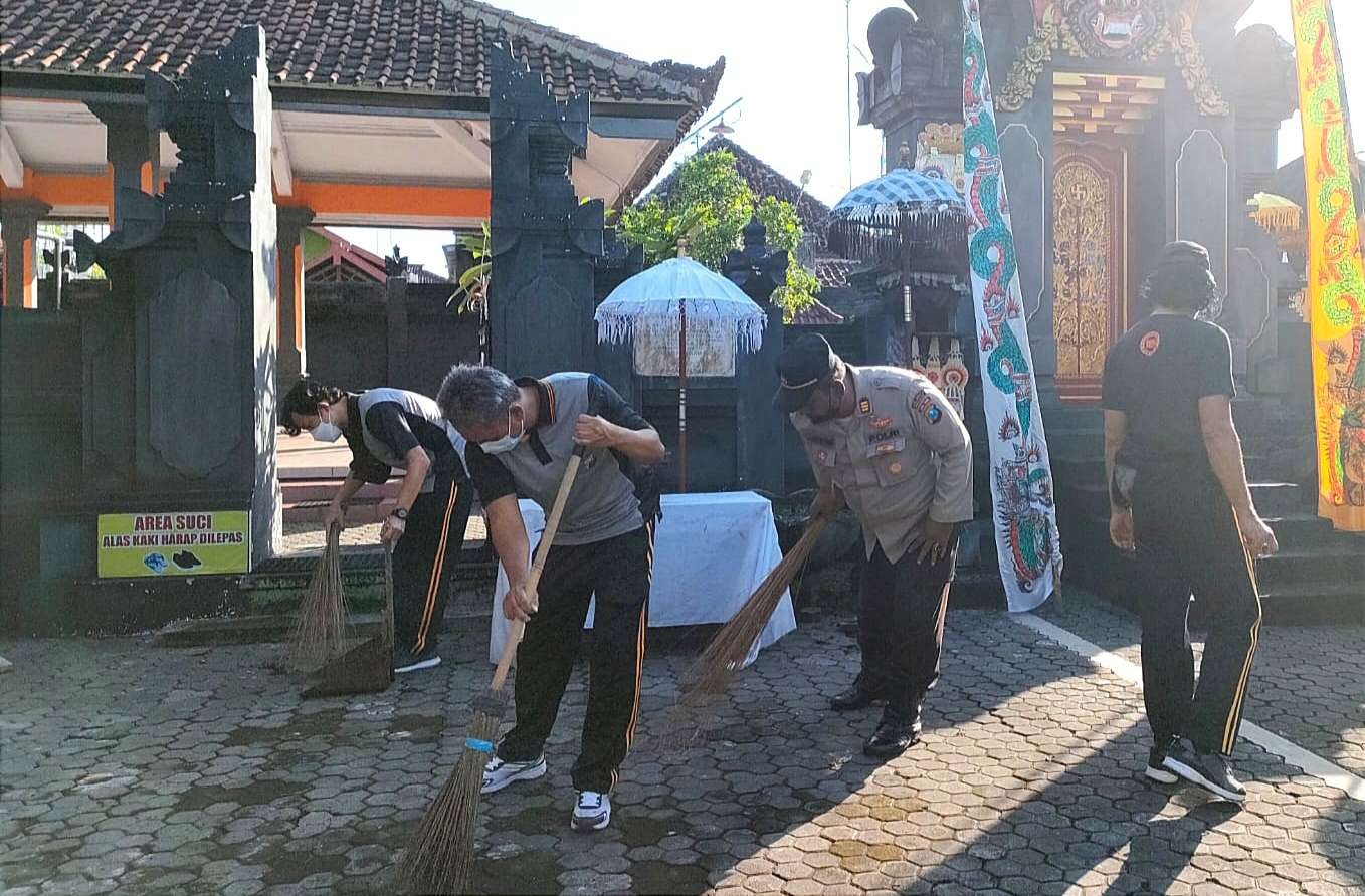 Sejumlah personel Polresta Banyuwangi membersihkan halaman salah satu Pura di Banyuwangi sebagai bagian dari Bakti Sosial Religi. (Foto: Istimewa)