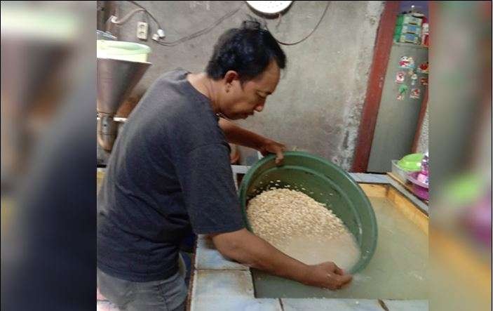 Ghofur Rohim saat mencuci kedelai. Ada perbedaan antara tempe produksi Kampung Tempe Tenggilis Kauman dulu dan sekarang. (Foto: Penulis: Sidhiq M AsySyifa dan  Bagas Wahyu A untuk Ngopibareng.id)