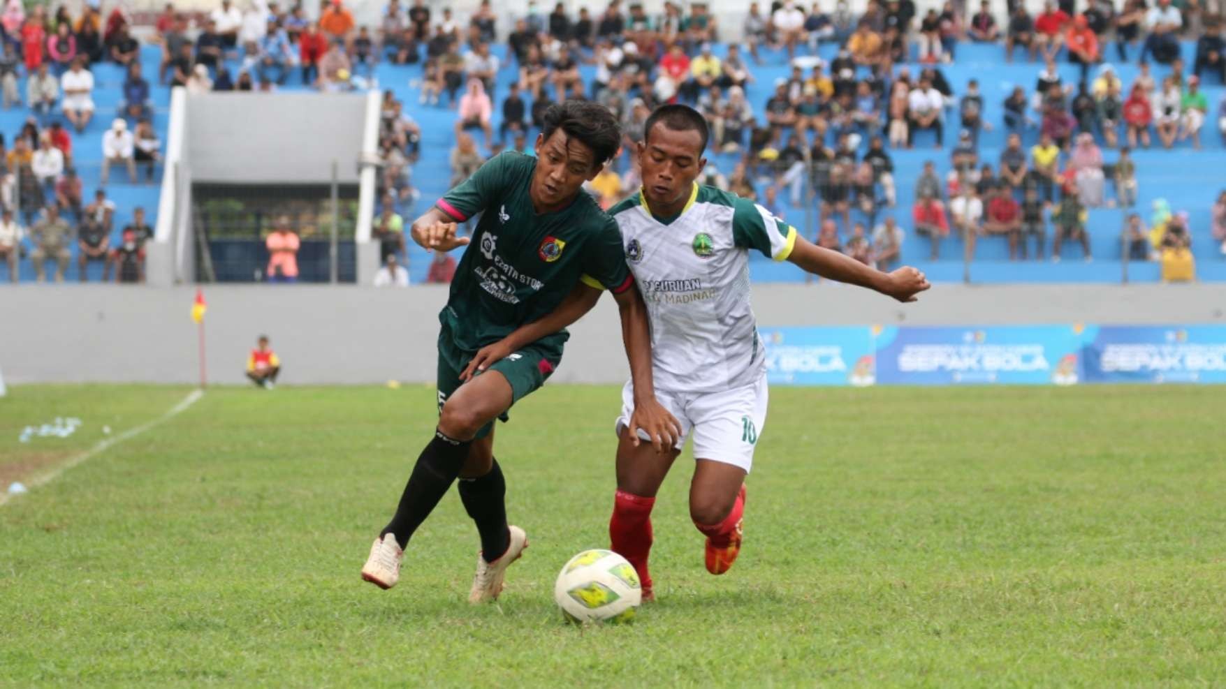Pemain Jember, Azril Fajar Shodiq (hijau) berebut bola dengan pemain Kota Pasuruan, Tegar Ilhamsyah (putih) di babak 8 besar Porprov Jatim VII di Stadion Notohadinegoro, Jember, Senin 27 Juni 2022. (Foto: Fariz Yarbo/Ngopibareng.id)
