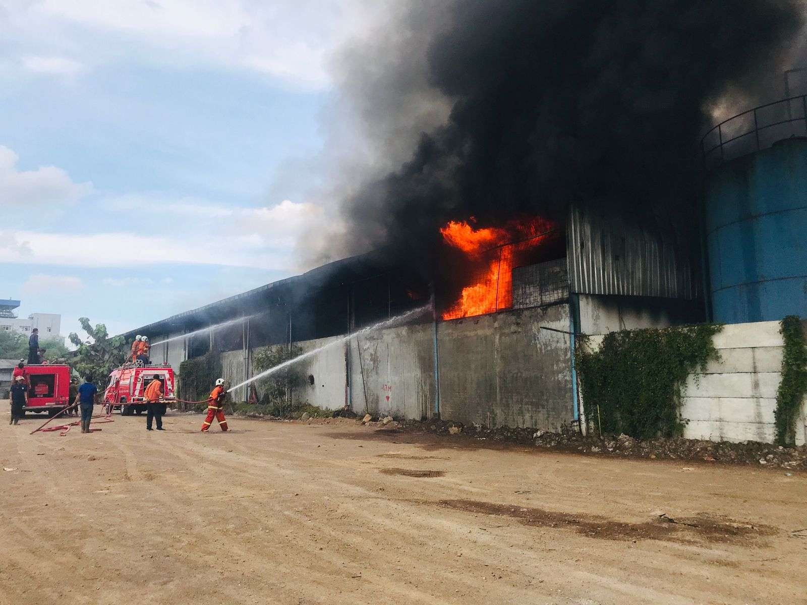 Petugas memadamkan api di Pabrik Minyak Kelapa di Mojokerto.(Deni Lukmantara/Ngopibareng)