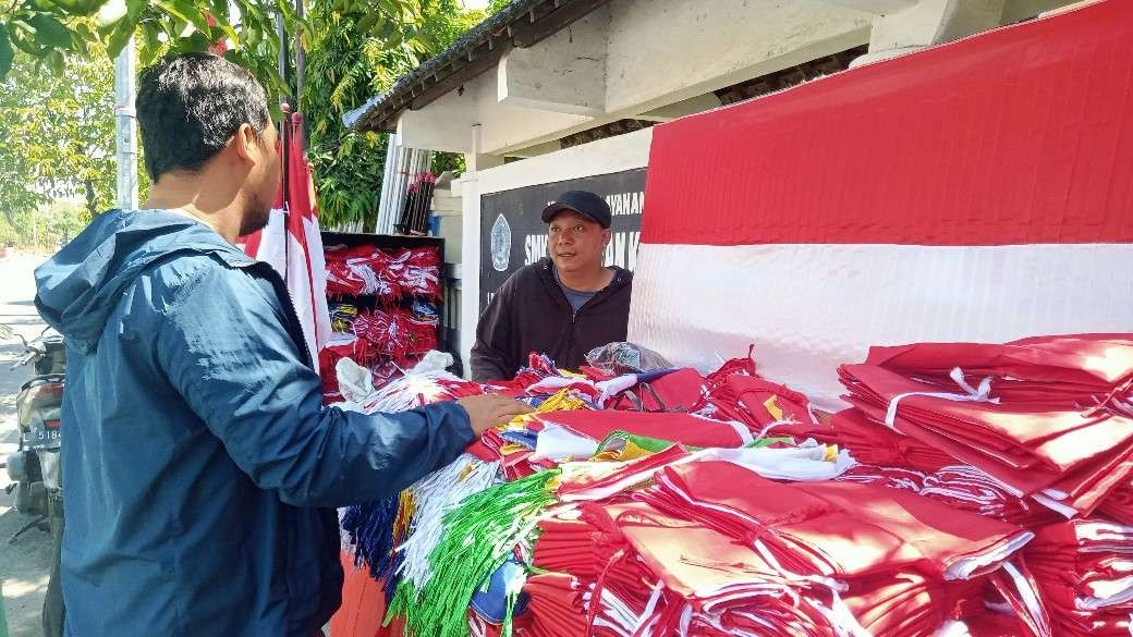 Penjual bendera merah putih di Tuban sedang melayani pembeli. (Foto: Khoirul Huda/Ngopibareng.id)