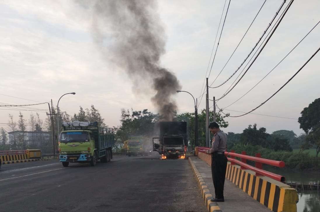 Petugas kepolisian di lokasi kejadian truk box isi mie instan yang terbakar di jembatan Jalur Pantura Tuban tepatnya Desa Bunut, Kecamatan Widang, Kabupaten Tuban, Kamis 28 Juli 2022. (Foto: Dokumentasi Polsek Widang)