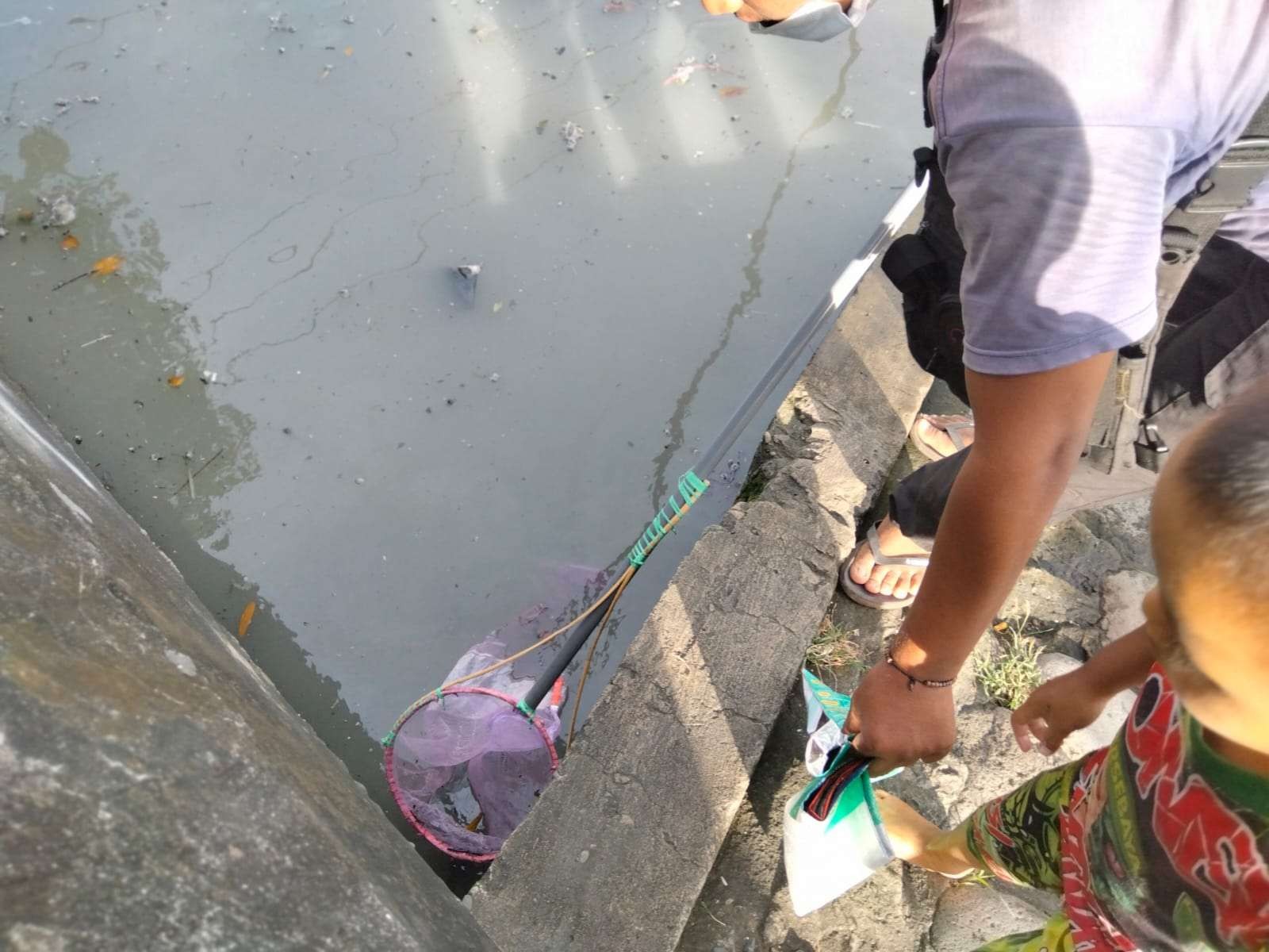 Warga menjaring ikan mabuk di pinggir sungai terusan Kalimas Surabaya, Selasa 2 Agustus 2022. (Foto: Istimewa)