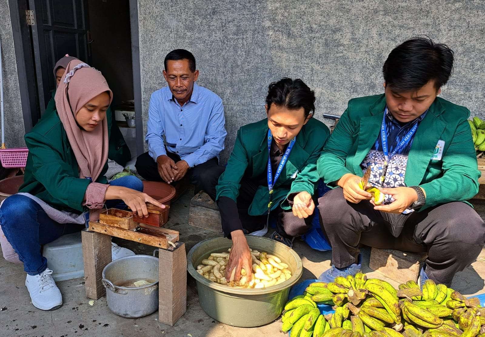 Amin Tohari (kemeja biru) saat memperhatikan mahasiswa KKN Unusa membuat keripik pisang dari pisang rejectnya. (Foto: Pita Sari/Ngopibareng.id)