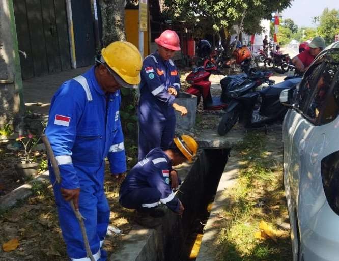 Petugas dari Pertamina EP Field Cepu berada di lokasi luberan minyak di selokan jalan Cepu - Blora (Foto: Ahmad Sampurno /Ngopibareng.id)