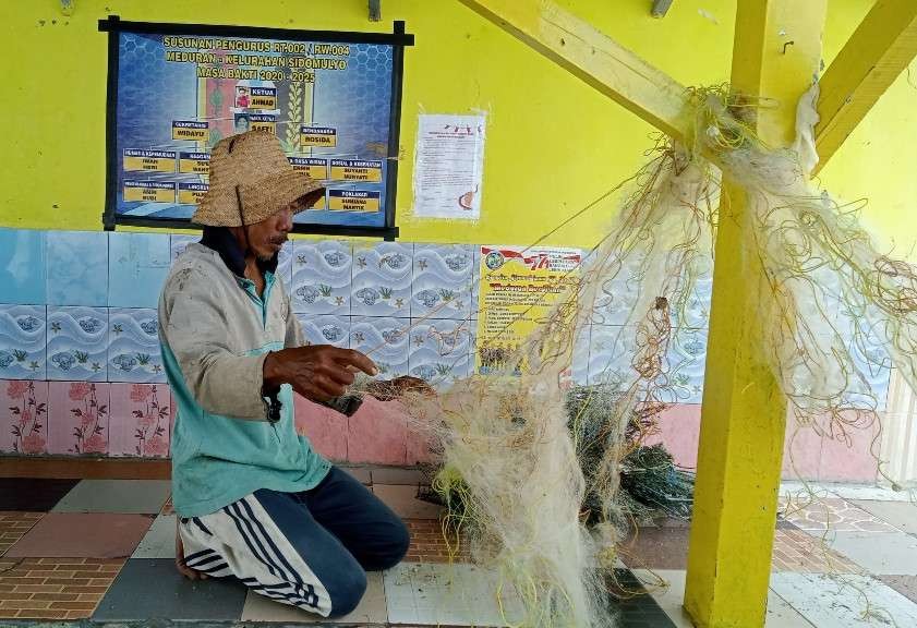 Nelayan tradisional di Kelurahan Sidomulyo, Tuban tidak melaut, namun hanya melakukan aktifitas memperbaiki jaring (Foto: Khoirul Huda/Ngopibareng.id)