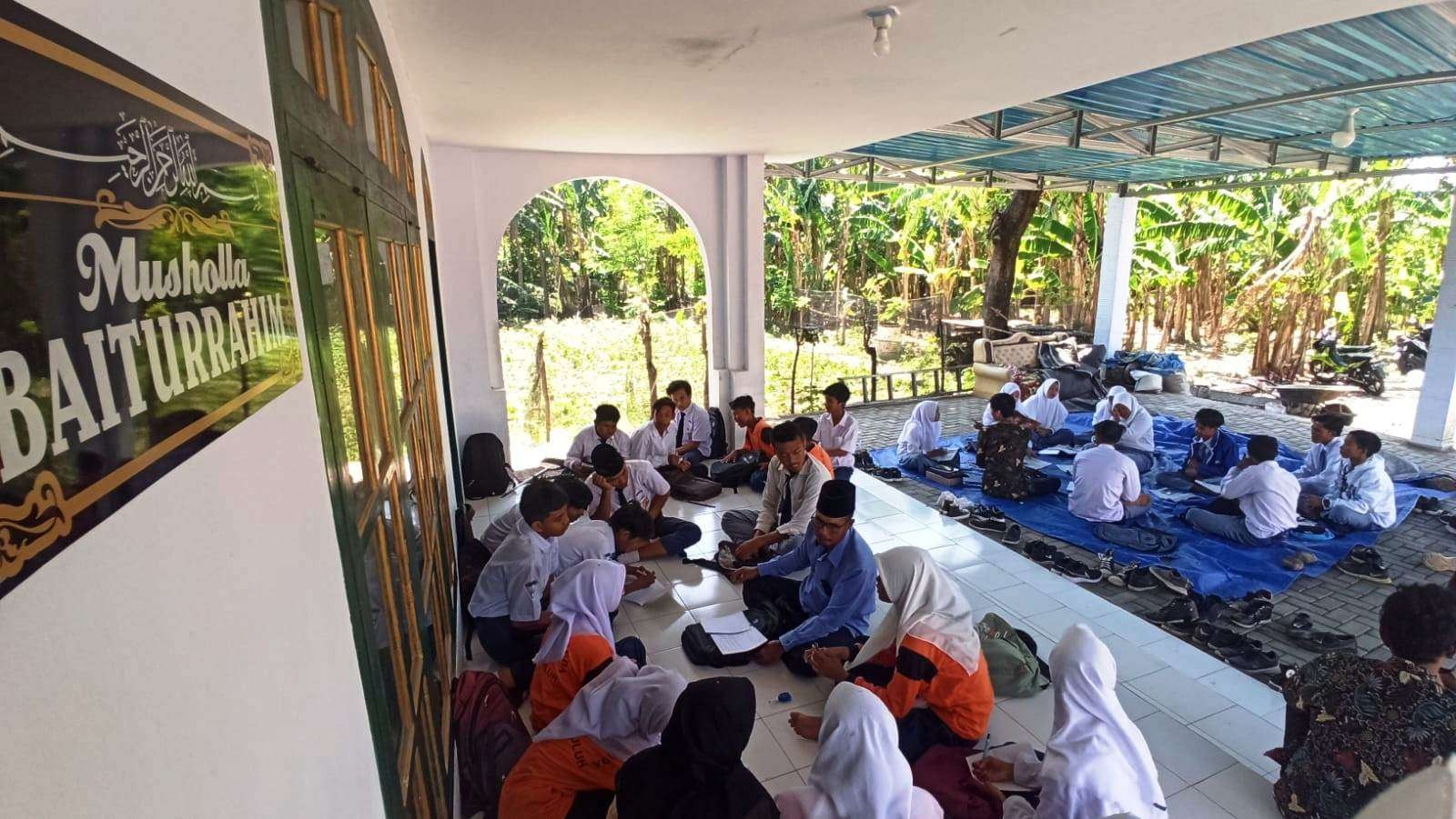 Puluhan murid MA dan MTs Darul Huda, Desa Alasbuluh, Kecamatan Wongsorejo belajar di Musala Baiturrahim, sejak sekolahnya disegel. (Foto: Muh Hujaini/Ngopibareng.id)