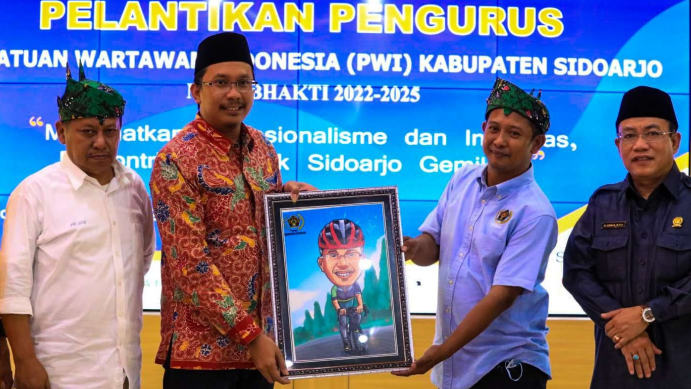 Mustain (baju biru) memberikan karikatur ke Bupati Sidoarjo Ahmad Muhdlor. (Foto: Aini/Ngopibareng.id)