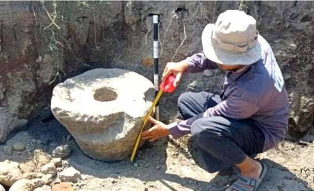 Juru pelihara Situs Lesong Situbondo mengukur Batu Lumpang zaman prasejarah ditemukan di tambang pasir.(foto: humas polres Situbondo)