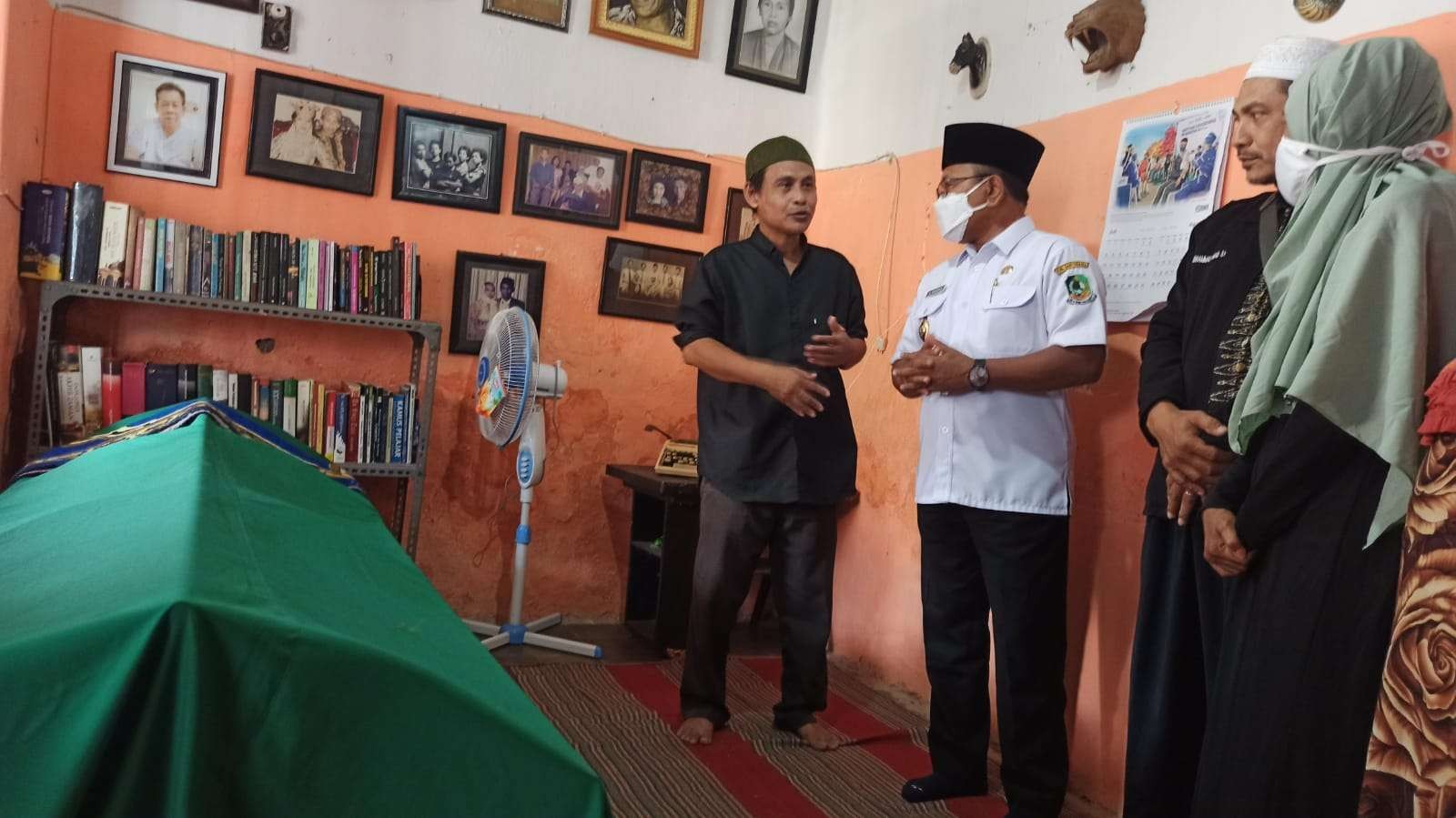 Wakil Bupati Banyuwangi Sugirah berbincang dengan putra Budayawan Hasnan Singodimajan, Bonang Prasunan, di rumah duka sebelum jenazah dimakamkan. (Foto: Muh Hujaini/Ngopibareng.id)