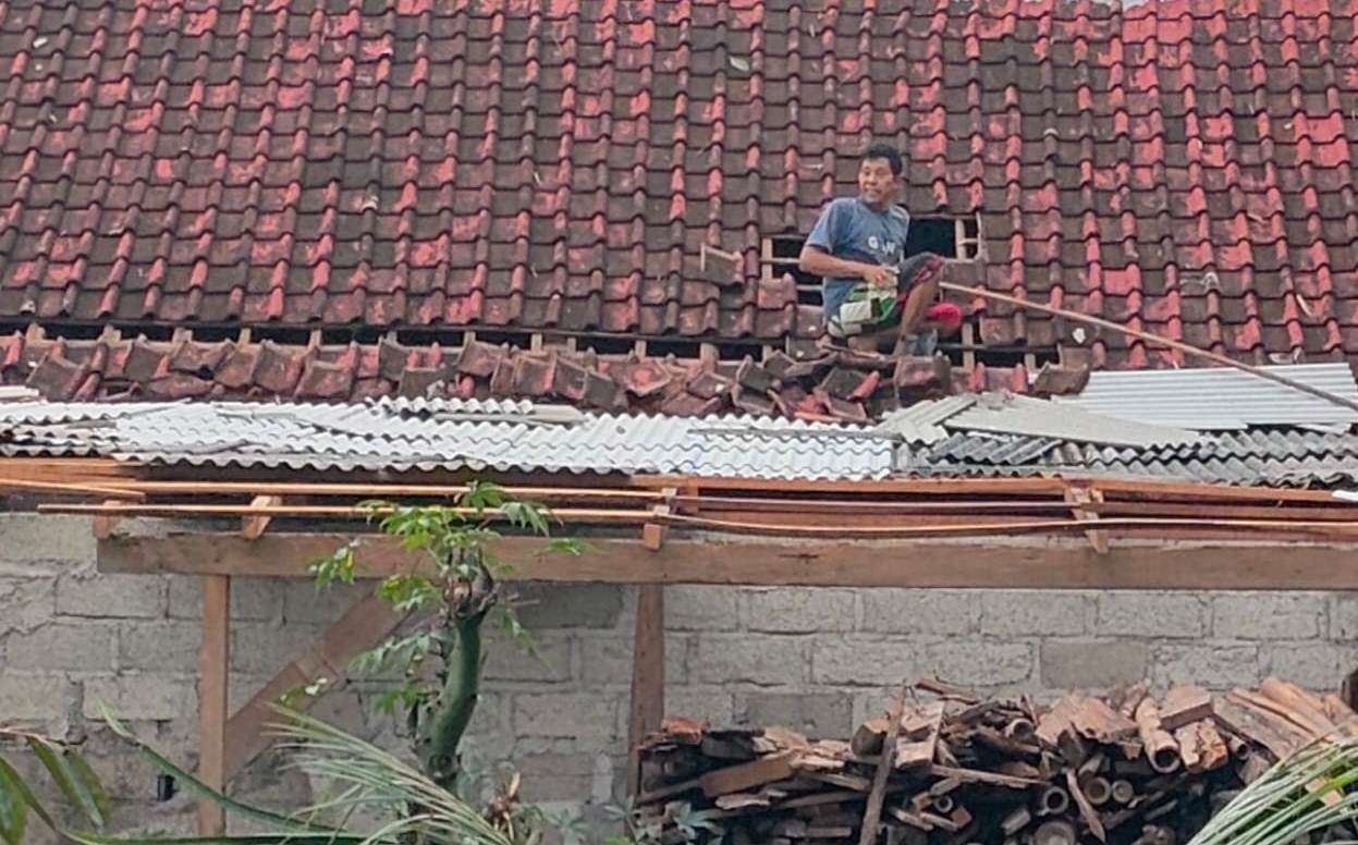 Salah seorang warga memperbaiki kerusakan pada bagian atap rumahnya setelah diterjang angin puting beliung. (Foto: Istimewa)