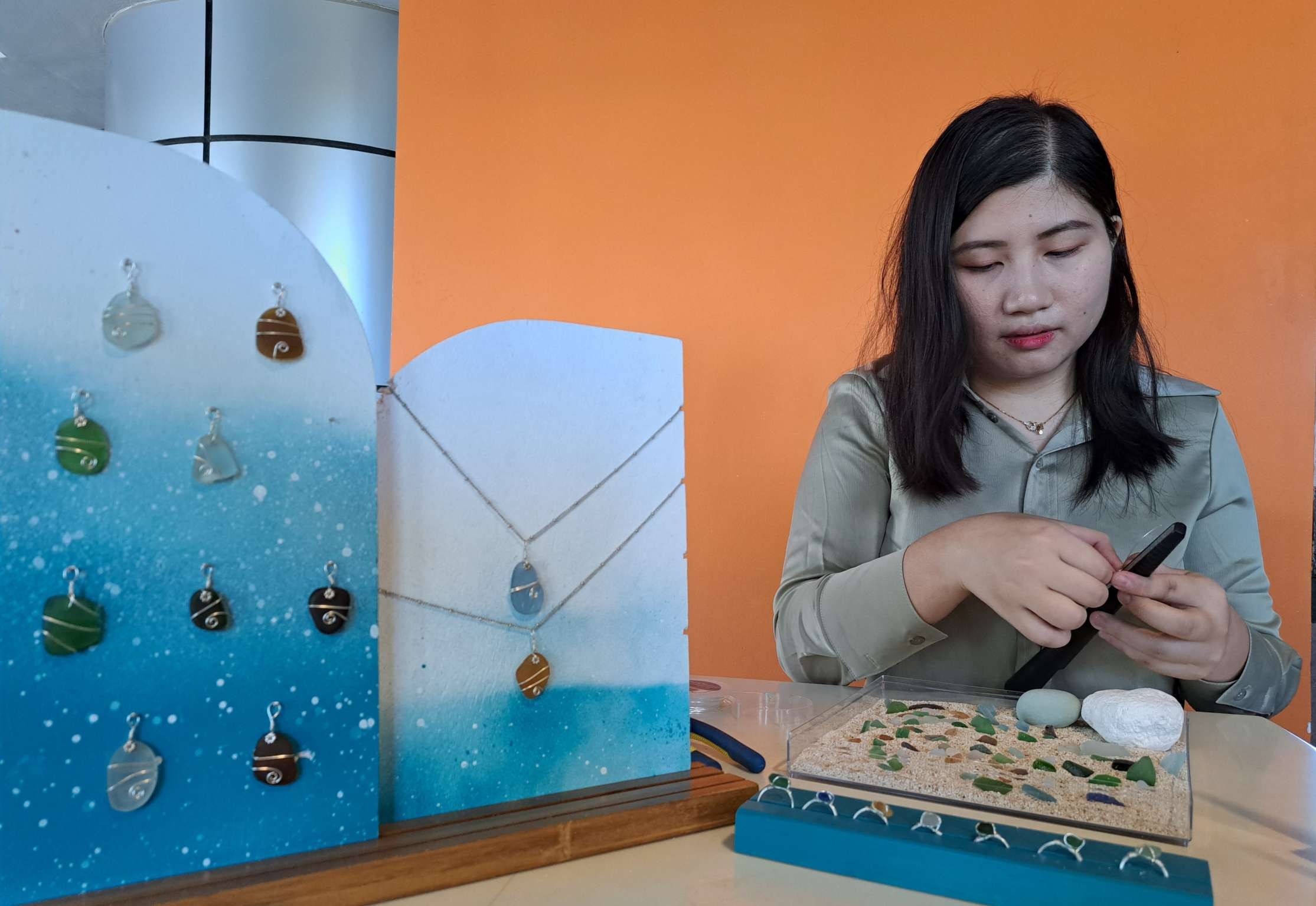 Athalia Michelle saat menunjukan koleksi perhiasaan dari seaglass dan cara pembuatannya. (Foto: Pita Sari/Ngopibareng.id)