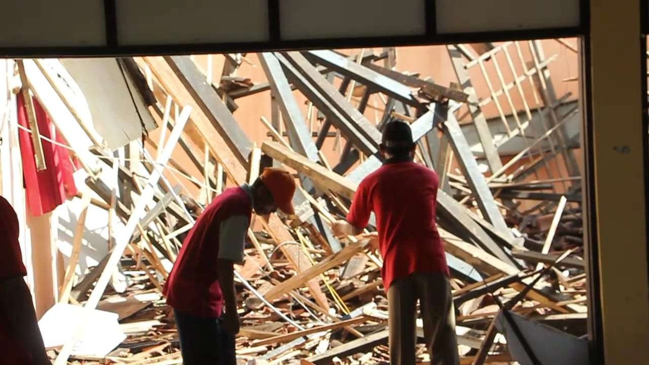 Dua orang tampak di antara reruntuhan atap bangunan gedung (Foto: Ahmad Sampurno/Ngopibareng.id)