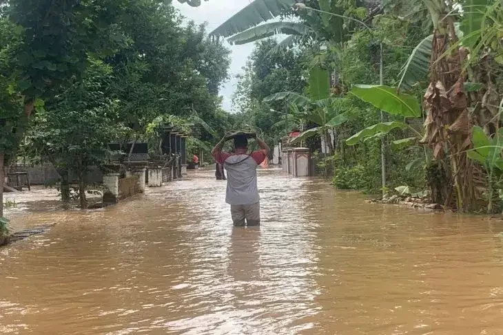 Warga melintasi jalan desa yang terendam banjir di Desa Jabung, Ponorogo, Sabtu 8 Oktober 2022. (Foto: antaranews. com)