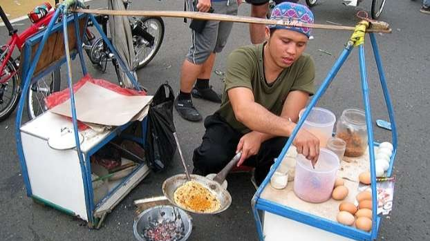 Bang Maman, pedagang kerak telur di kawasan Kemayoran dengan gerobak pikulannya yang khas, melanjutkan warisan orang tua. (Foto: Asmanu Sudharso/Ngopibareng.id)