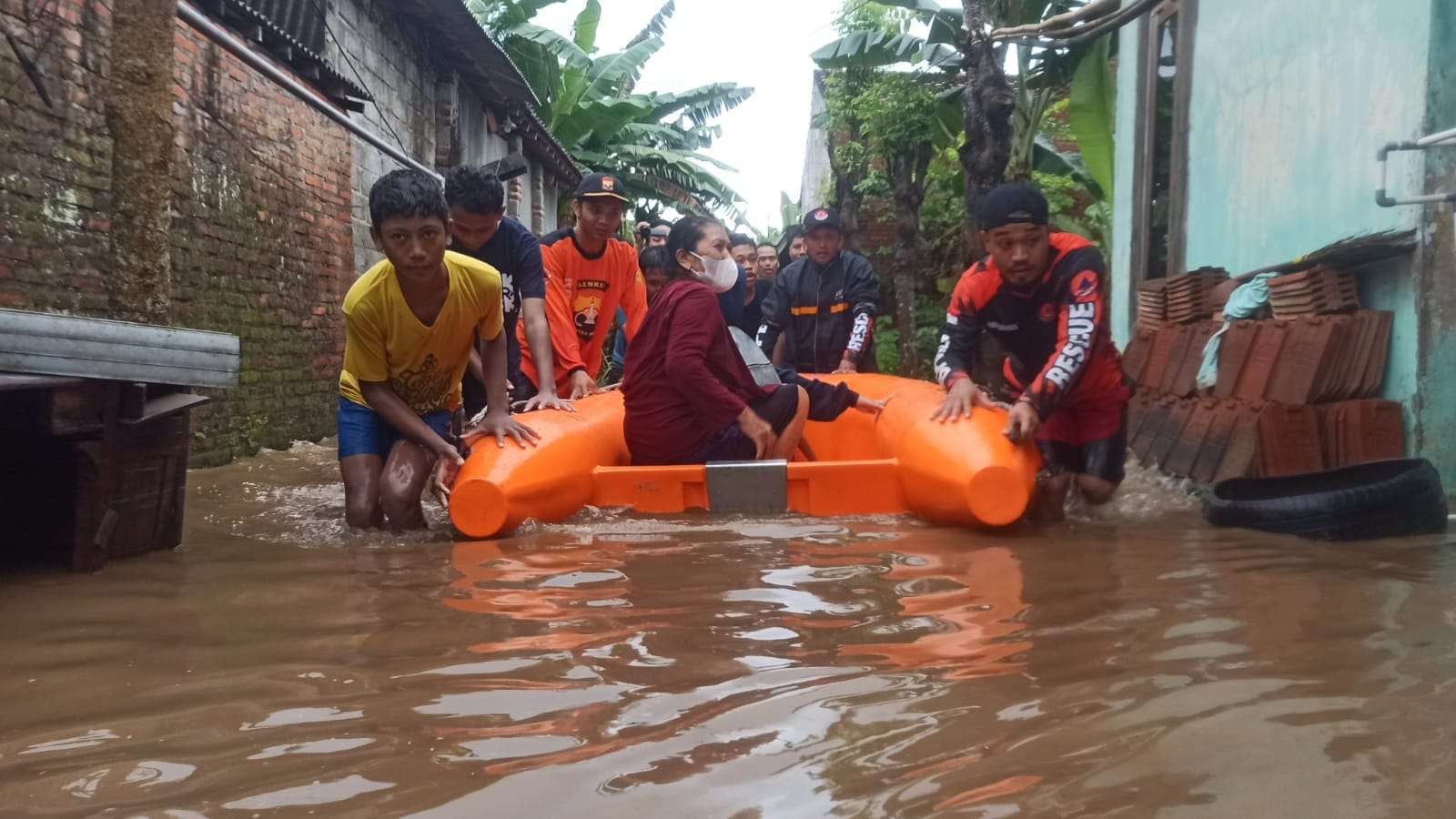 Petugas BPBD dan relawan mengevakuasi warga yang rumahnya terendam air (foto:Muh Hujaini/Ngopibareng.id)