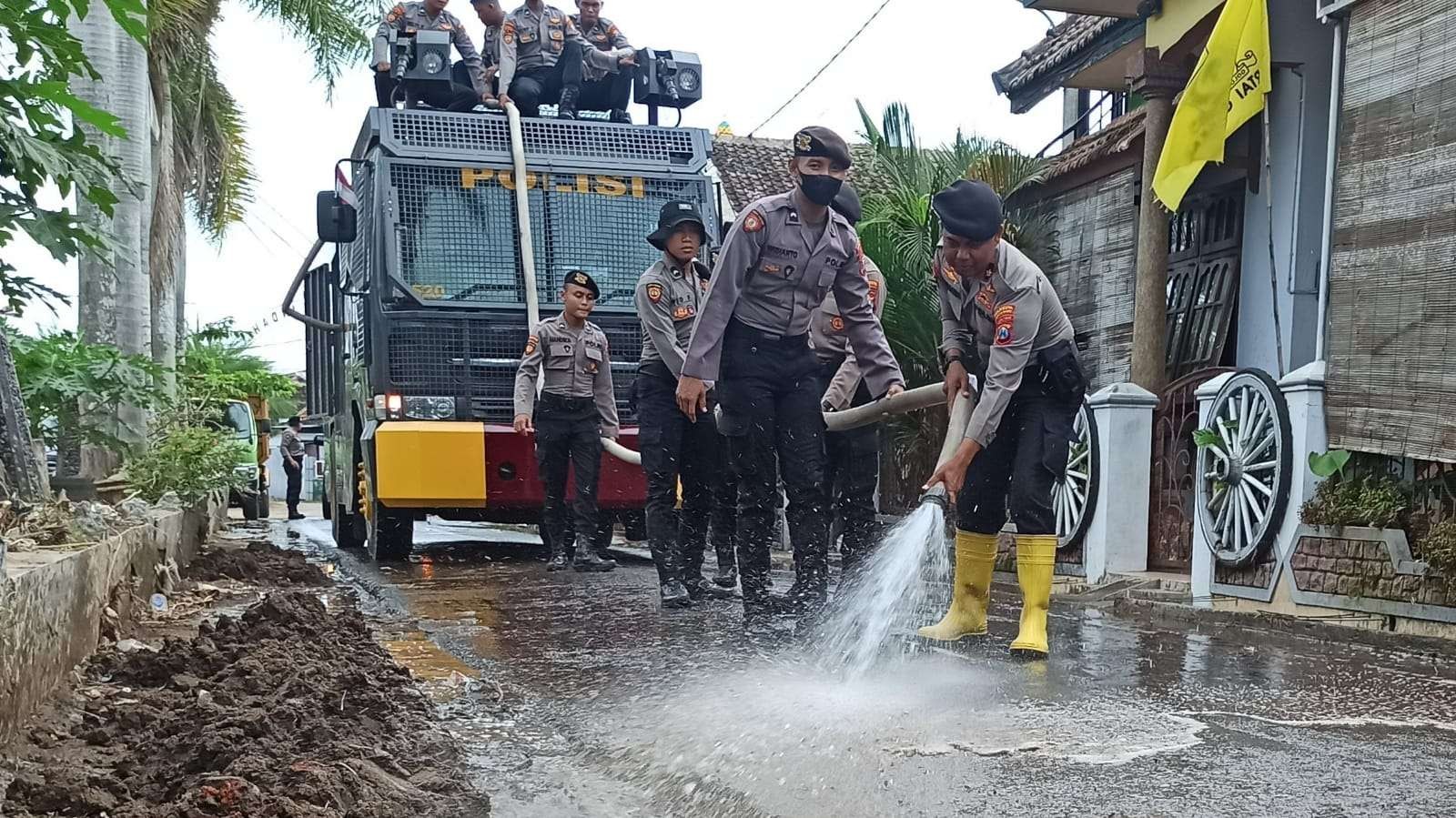 Personel Sabhara Polresta Banyuwangi membersihkan sisa lumpur akibat banjir dengan watercannon (Foto: Muh Hujaini/Ngopibareng.id)