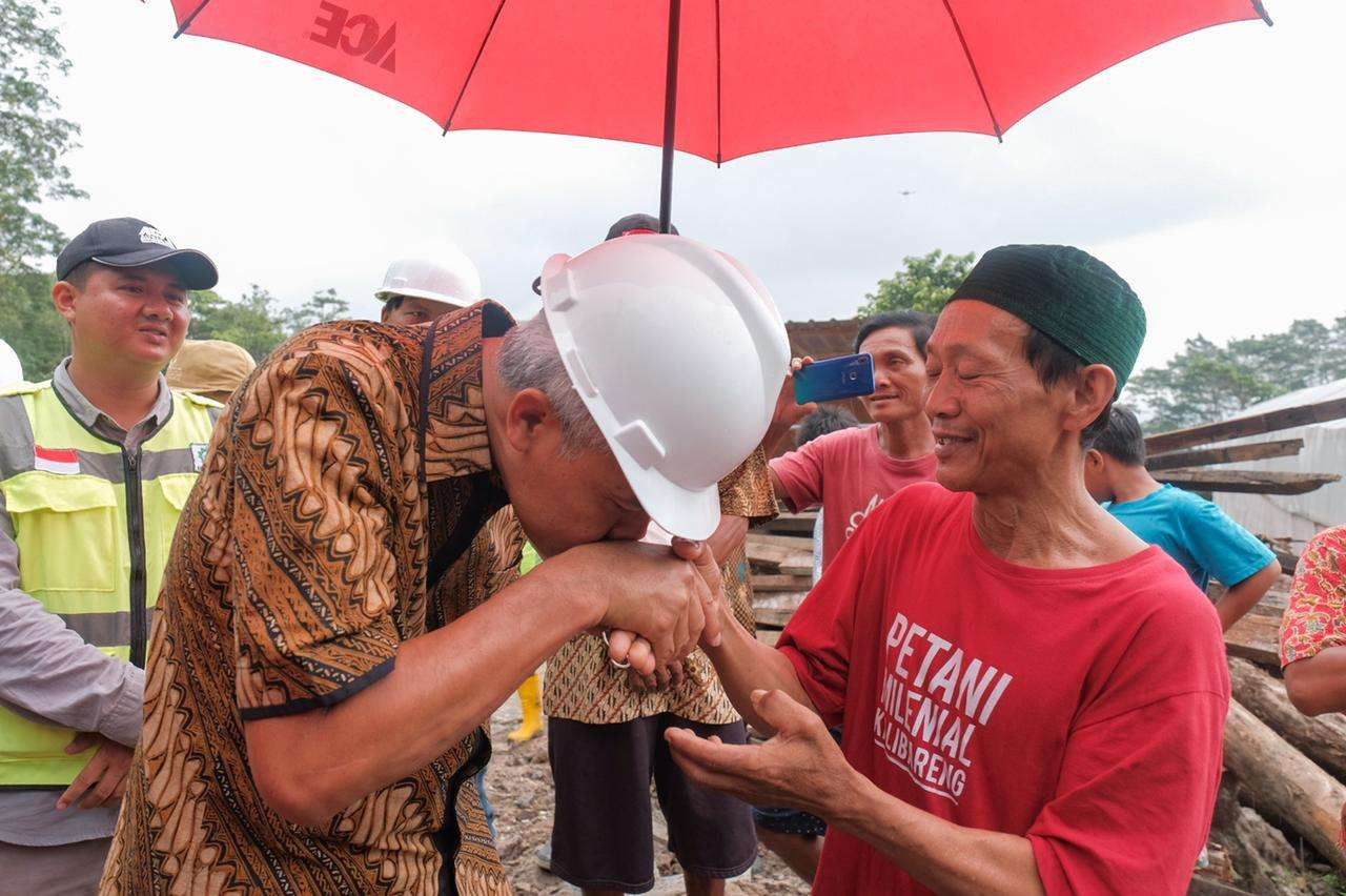 Gubernur Jawa Tengah, Ganjar Pranowo cium tangan petani bernama Subari. Ia telah menghibahkan tanahnya untuk pembangunan embung. (Foto: Diskominfo Pemprov Jateng)