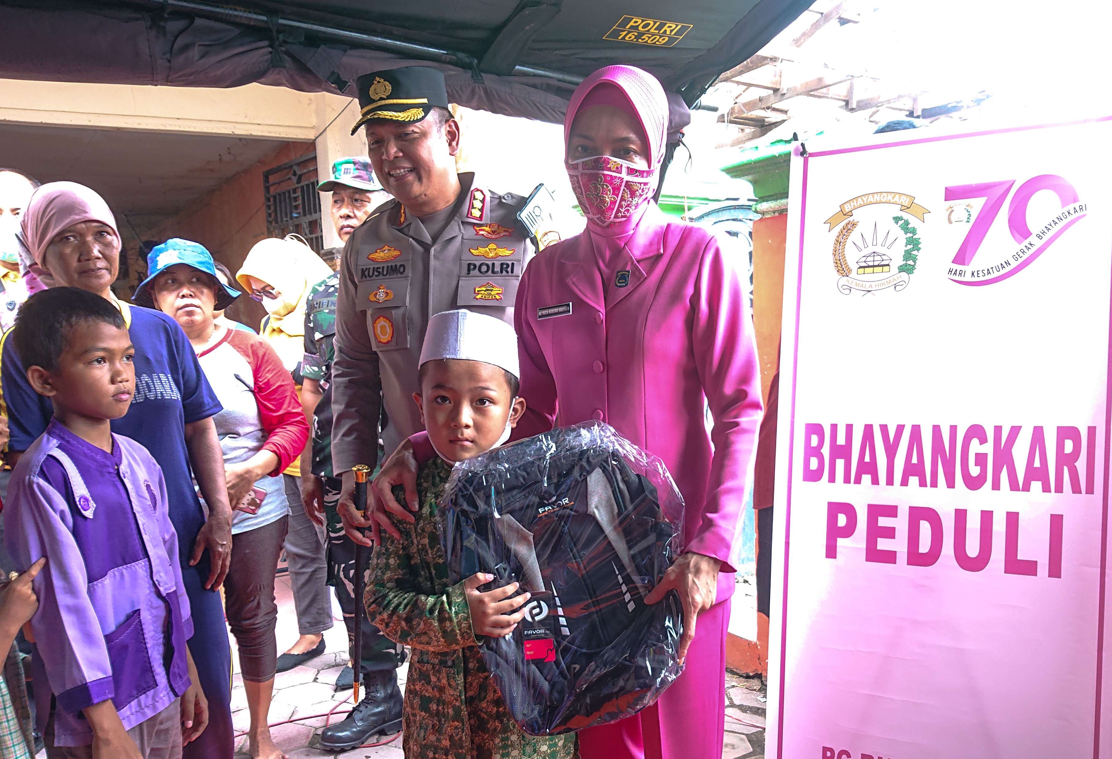 Kapolresta Sidoarjo Kombes Pol Kusumo Wahyu Bintoro bersama istri bagikan tas sekolah kepada anak-anak di pengungsian (Foto : Aini/Ngopibareng.id)