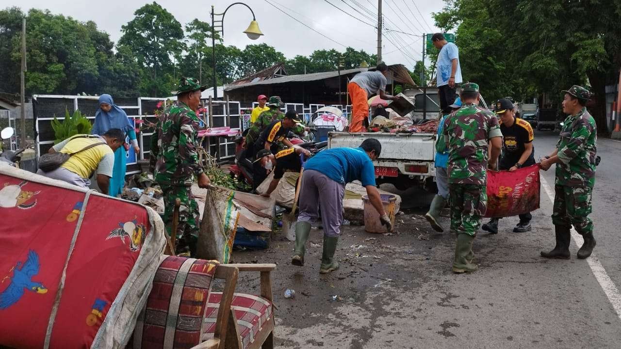 Sejumlah personil TNI membantu warga melaksanakan pembersihan sisa-sisa sampah akibat banjir yang terjadi Senin kemarin (foto: Muh Hujaini/Ngopibareng.id)