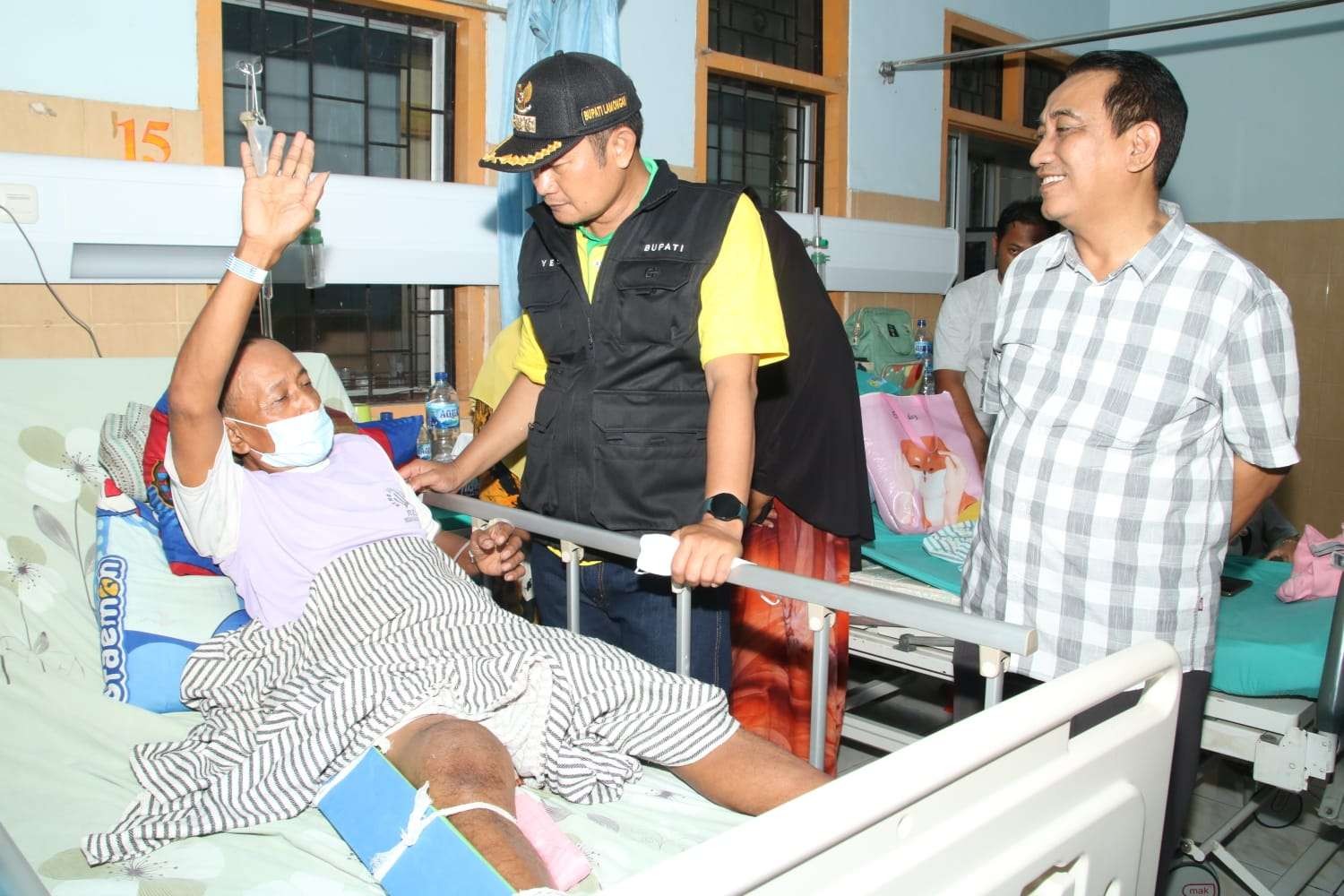 Bupati Lamongan, Yuhronur Efendi didampingi Kadis Perhubungan Heruwidi saat besuk Riyanto, penyelamat pengendara motor yang nyaris tertabrak kereta api. (Foto: Istimewa)